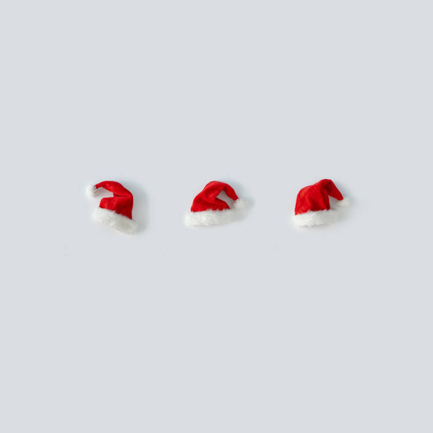 Chapéus de Papai Noel criativos em fundo claro. Inverno mínimo flat lay conceito de Natal
   - Foto, Imagem