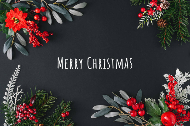 Marco de borde plano hecho de cosas naturales de invierno con texto Feliz Navidad sobre fondo oscuro
   - Foto, imagen