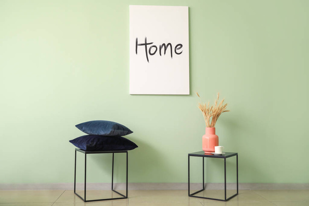 Mesas com travesseiros e vaso perto da parede de cor no quarto
 - Foto, Imagem