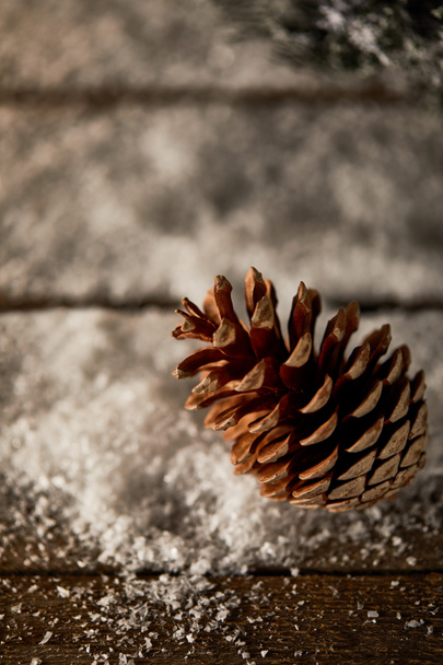 zbliżenie szyszki sosnowej na drewnianym stole ze śniegiem na Boże Narodzenie - Zdjęcie, obraz