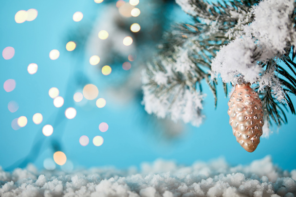 branches d'épinette dans la neige avec une boule de Noël cône de pin et lumières bokeh sur bleu
 - Photo, image