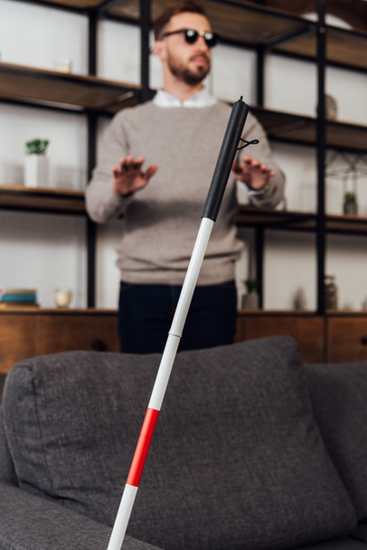 Selective focus of walking stick and blind man in living room - Foto, imagen