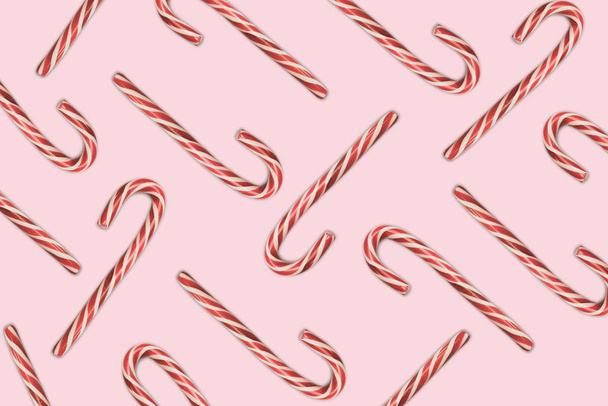 Beautiful striped hard candy cane staff on a pink table background. - Photo, Image