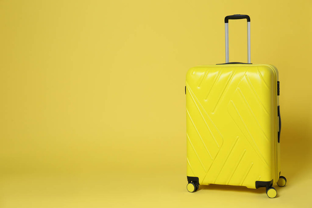 Stylish suitcase on yellow background. Space for text - 写真・画像