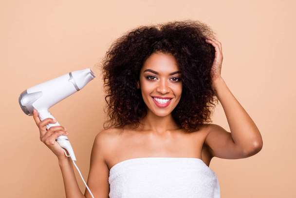 Close-up portrait of her she nice-looking attractive well-groomed cheerful cheery wavy-haired girl using electric dryer preparing for party isolated over beige pastel background - Foto, imagen