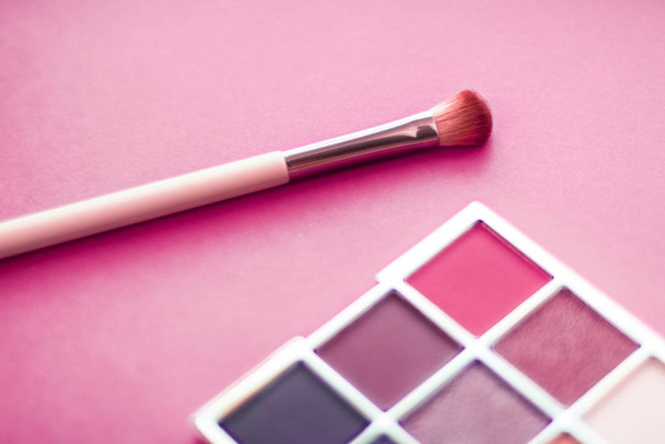 Palette de fards à paupières et pinceau de maquillage sur fond rose, pompon
 - Photo, image