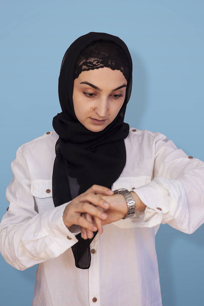 Başörtülü Arap kadın zamanı kontrol ediyor. Toplantıya geç kalan bir kadın kendini mutsuz hissediyor. Şaşırmış Orta Doğulu kızın portresi zamanı kontrol ediyor. - Fotoğraf, Görsel