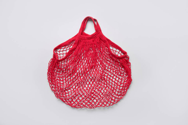 Empty red cotton eco mesh bag on grey. Eco friendly. - Fotó, kép