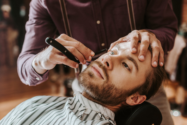selective focus of barber shaving handsome man  - Fotografie, Obrázek