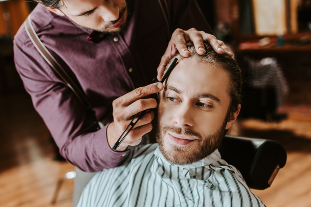 barber shaving happy bearded man in barbershop  - 写真・画像