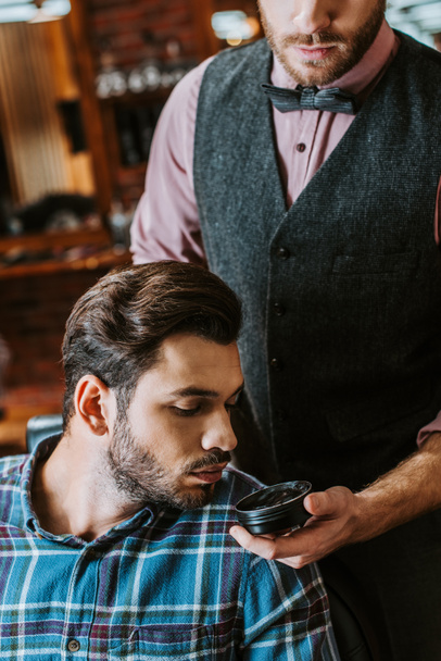 fryzjer gospodarstwa słoik z czarnymi włosami pomade blisko człowieka  - Zdjęcie, obraz
