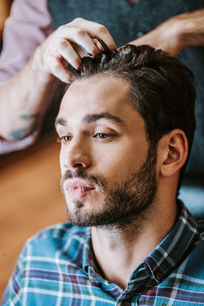 barber with black hair pomade on hands styling hair of handsome man  - Photo, Image