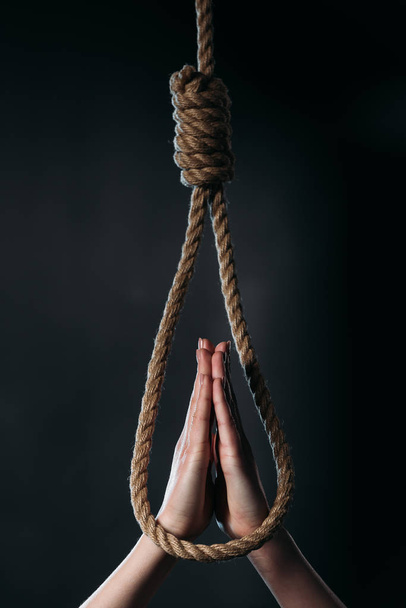 cropped view of woman showing pray gesture near hanging rope noose isolated on black - Fotoğraf, Görsel
