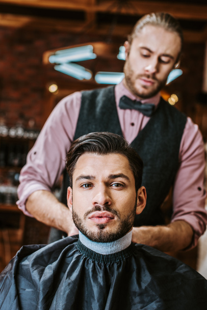 selective focus barber fixing collar around neck of man  - Foto, Imagem