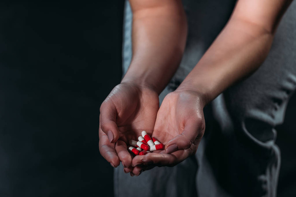 partial view of depressed woman holding handful of pills and going to commit suicide isolated on black - Photo, Image