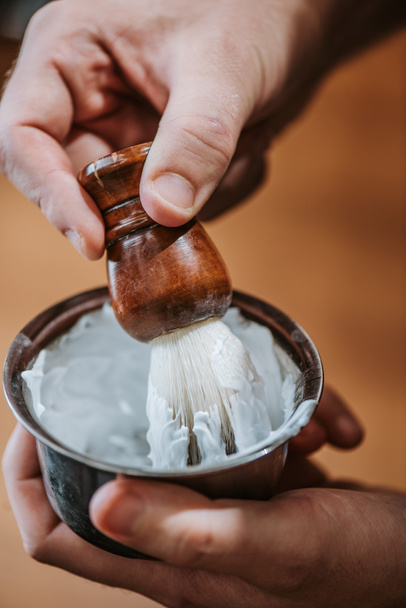 close up of barber holding shaving brush near bowl with white shaving cream  - Fotoğraf, Görsel