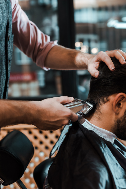 vue recadrée de coiffeur coiffant les cheveux de l'homme dans le salon de coiffure
  - Photo, image