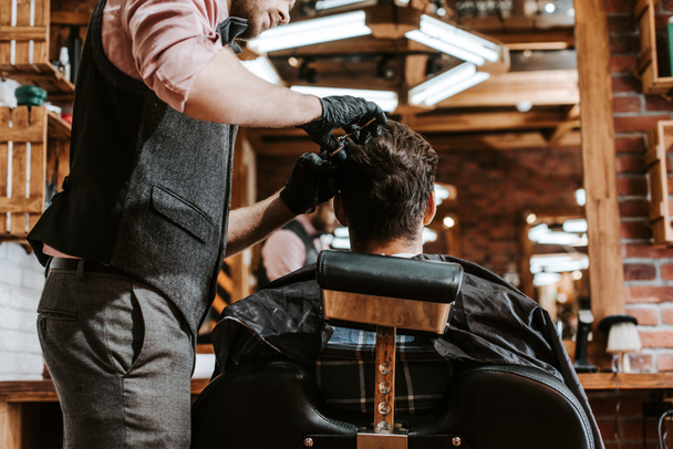 bearded barber cutting hair of man in barbershop  - Photo, Image