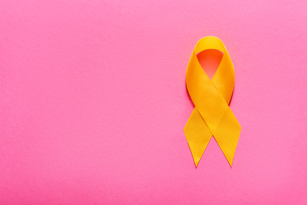 Ansicht von oben gelbes Bewusstseinsband auf rosa Hintergrund, Suizidpräventionskonzept - Foto, Bild