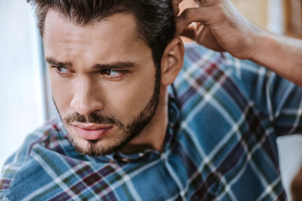 handsome bearded man touching hair in barbershop  - Photo, Image
