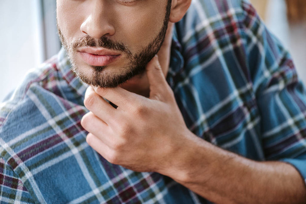 cropped view of bearded man touching face in barbershop  - Photo, Image