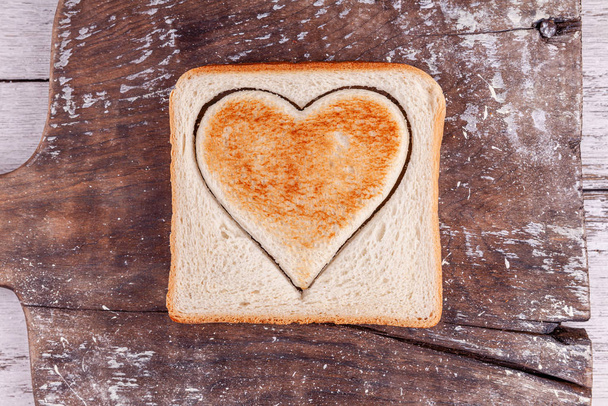 Toasted bread with cutted heart on vintage board, Happy Valentines Day concept - Foto, Bild