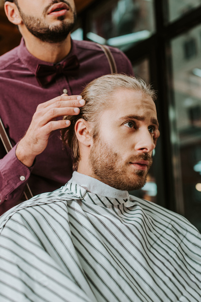barbe barbier toucher les cheveux de bel homme dans le salon de coiffure
  - Photo, image