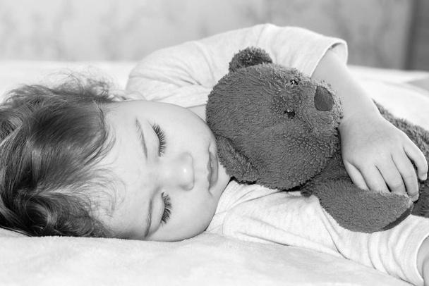 Bambino che dorme abbracciando un orsacchiotto, ritratto da primo piano. Ragazzo caucasico ragazza sognando nel pomeriggio
 - Foto, immagini