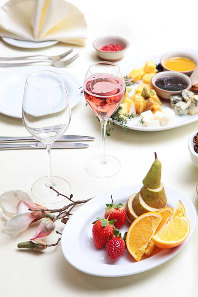 The fruit on the plate and pink champagne on the table set for the holiday. - Foto, afbeelding