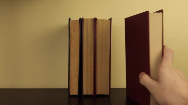 una mano del hombre pone los libros en el estante uno tras otro en una posición vertical
 - Metraje, vídeo