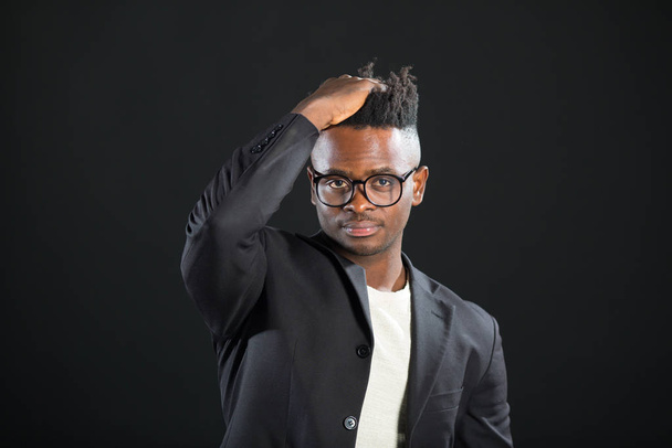 handsome african man in a suit with glasses on a black background - Zdjęcie, obraz