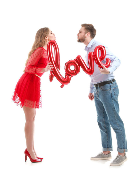 Beyaz arka planda aşk kelimesi şeklinde balonları olan mutlu genç bir çift. Sevgililer Günü kutlaması - Fotoğraf, Görsel