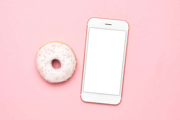 Mobile phone and sweet strawberry donuts on pink background flat lay - Fotoğraf, Görsel