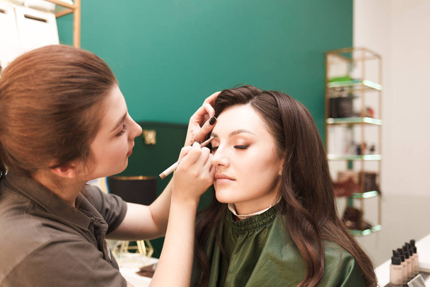 Maquiagem artista faz maquiagem sobrancelha para seu cliente. Procedimento de desenho de sobrancelha
 - Foto, Imagem