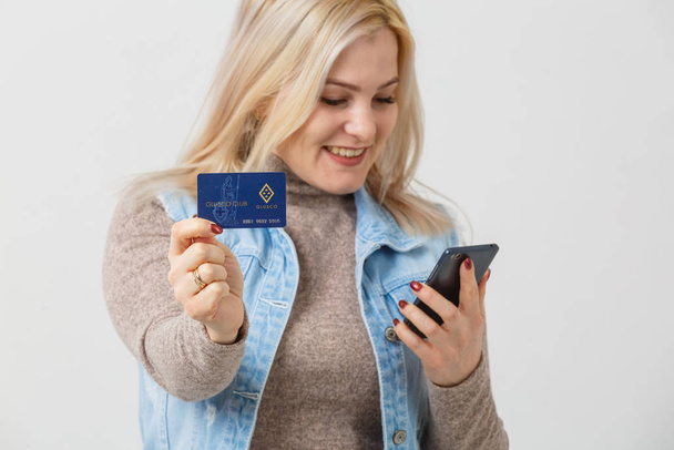 Lady buying online with a credit card and smart phone isolated white background - 写真・画像