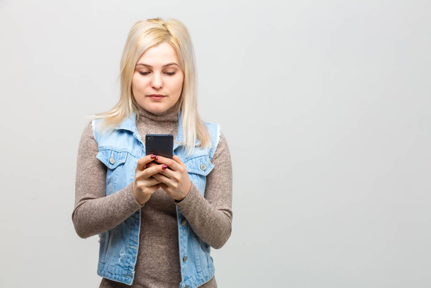 Blonde fille avec téléphone portable. Portrait de femme avec smartphone. fond blanc isolé
 - Photo, image