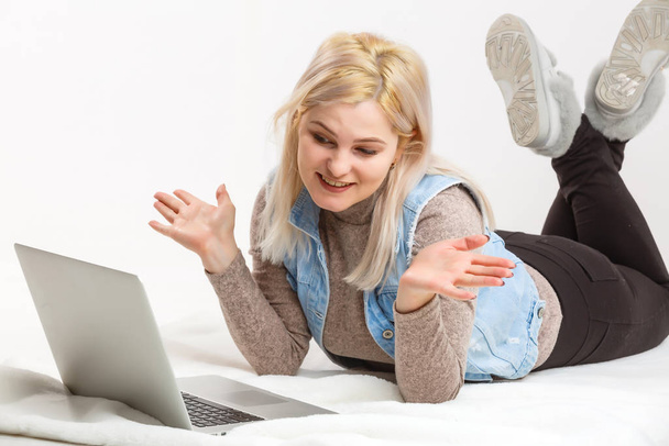 fille heureuse se trouve sur le sol avec un ordinateur portable près du mur de lumière
 - Photo, image