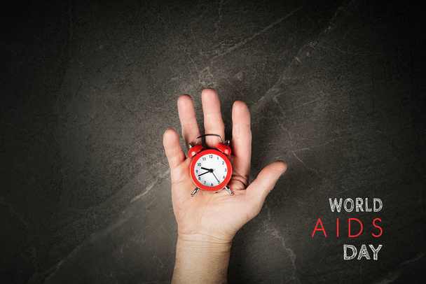 Punainen herätyskello käsissä maailmassa AIDS päivä
 - Valokuva, kuva