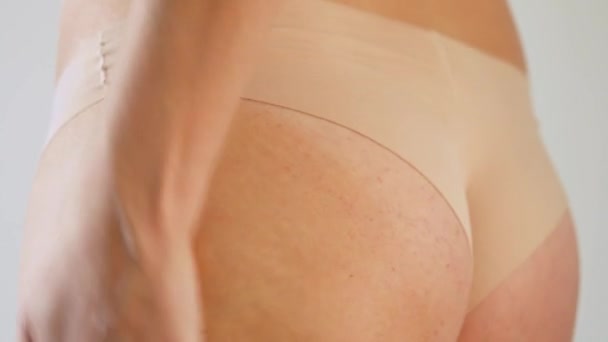 Kobieta pociera krem antycellulitowy o skórę pośladków - Materiał filmowy, wideo