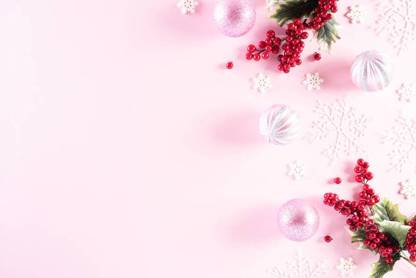 Concetto di sfondo natalizio. Vista dall'alto della palla di Natale con fiocchi di neve e bacche rosse su sfondo pastello rosa chiaro
. - Foto, immagini