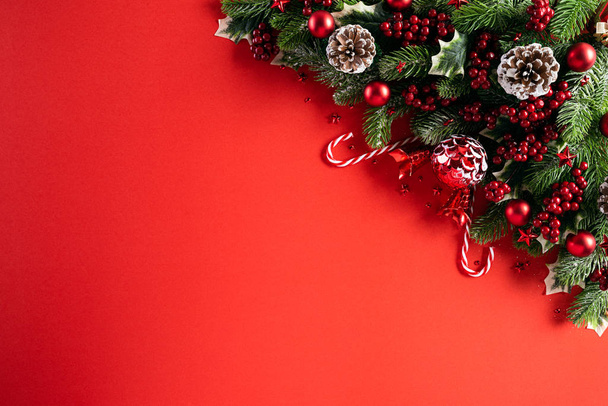 Concepto de fondo de Navidad. Vista superior de la caja de regalo de Navidad bolas rojas con ramas de abeto, conos de pino, estrella de bayas rojas y campana sobre fondo rojo. - Foto, Imagen