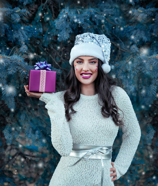 Young woman in Santa hat posing with gift - Foto, imagen