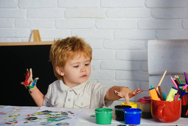 Ujj festés. A fiú megérinti a színes festéket az ujjaival. Rajzolás élénk színekkel. Korai fejlődés. Iskola gyerekeknek. - Fotó, kép