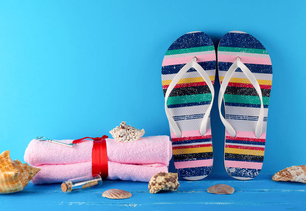pair of female beach slippers and a towels on a blue background - Fotó, kép