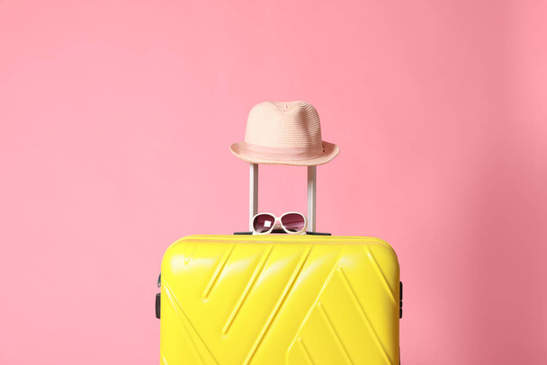 Yellow suitcase with sunglasses and hat on pink background - Fotoğraf, Görsel