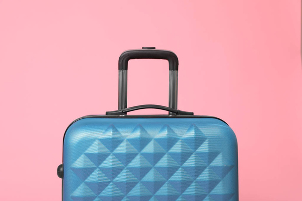 Stylish blue suitcase packed for travel on pink background - 写真・画像
