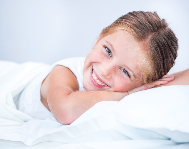 little smiling girl in a bed - Foto, afbeelding