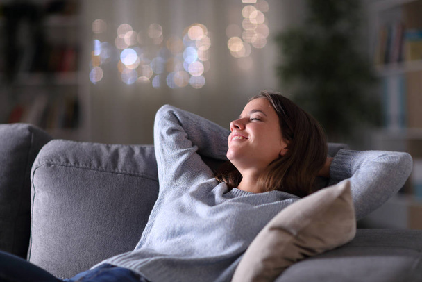 Happy woman relaxing sitting on a couch in the night at home - Фото, зображення