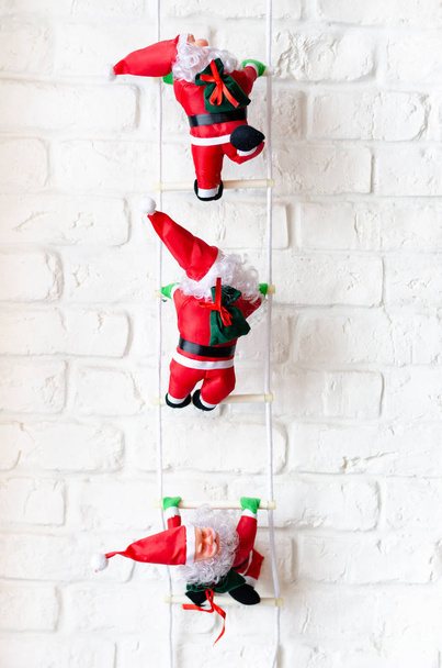 Arrampicata rosso Babbo Natale sulla scala torna parete di mattoni bianchi
 . - Foto, immagini