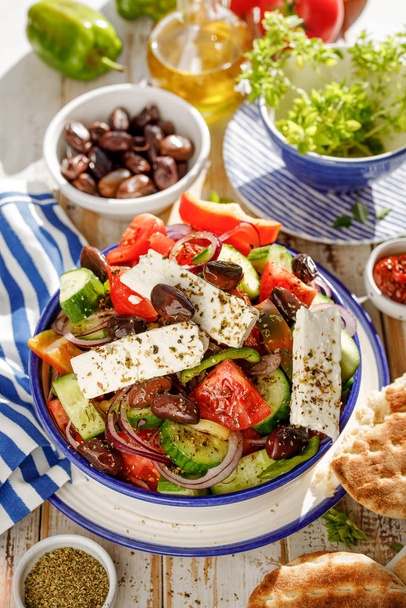 Greek salad. Traditional Greek salad consisting of fresh vegetables such as tomatoes, cucumbers, peppers, onions, oregano and olive oil. A delicious and healthy vegetarian, mediterranean dish - 写真・画像